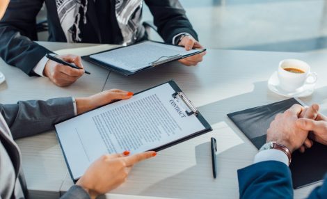 cropped view of business partners holding contract on meeting in office